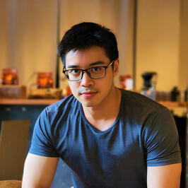 Profile photo of Yee Heng Yeh: dressed in dark grey t-shirt, short black hair, and black-rimmed glasses, warm background